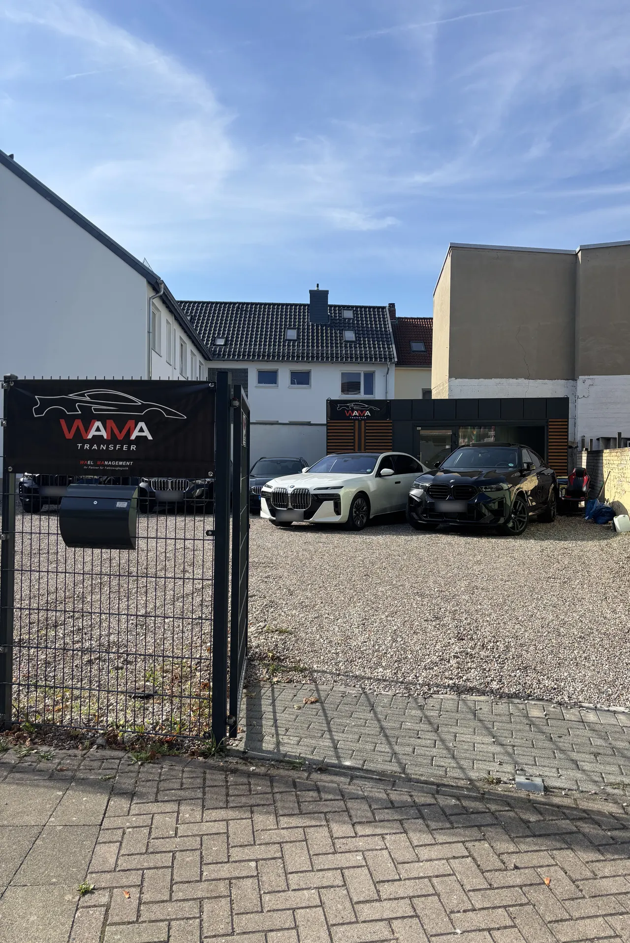 Einfahrt zum Hof mit WaMa Transfer Banner am Tor